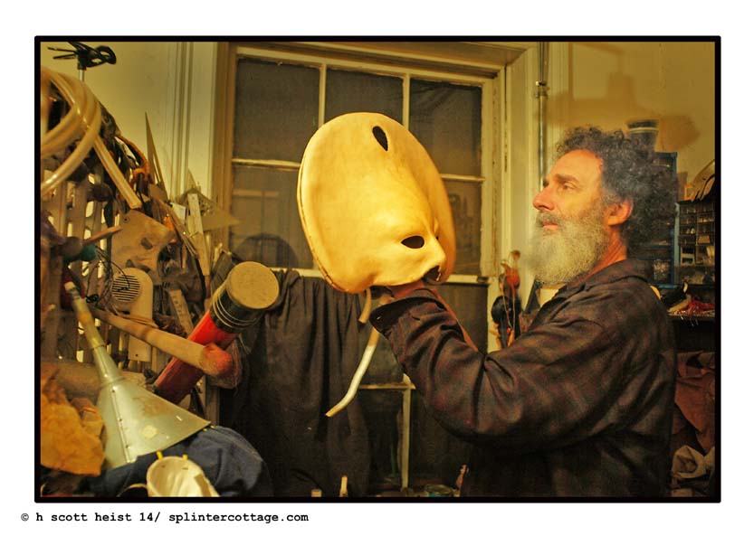 Stanley holding the Queen of the Night Mask before color and detail added.  Leather mask, with mask maker Stanley Allan Sherman holding it from the inside  as he looks at it.   There is a back and front of the mask that come apart in the middle on the edge.  Photo taken in Stanley's Mask Arts   Company  Studios